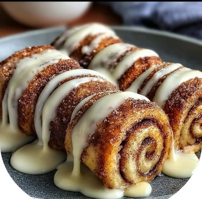 Cinnamon roll French toast roll-ups served on a plate with syrup and fruit