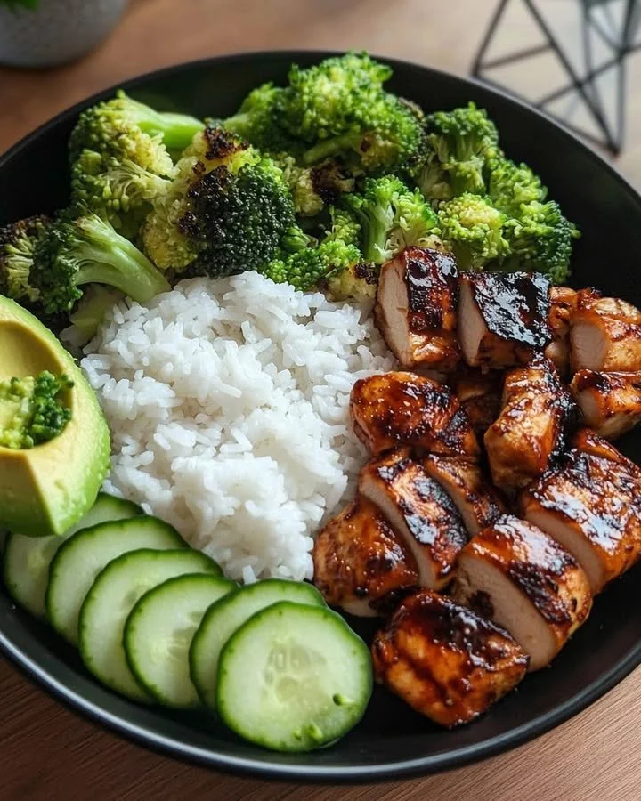 Glazed teriyaki chicken rice bowl with broccoli, avocado, and cucumber.