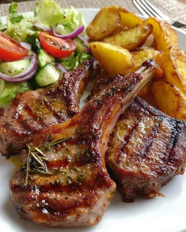 Herb-grilled lamb chops served with golden potato wedges and cucumber salad