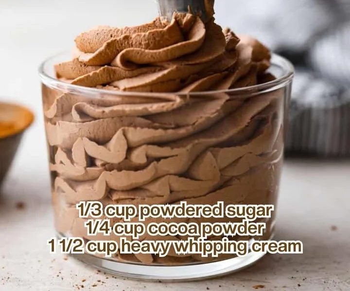 A bowl of homemade whipped cream with a whisk and fresh strawberries