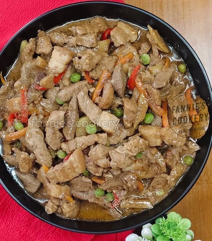 Delicious Pork IGADO served on a plate with vegetables and sauce.