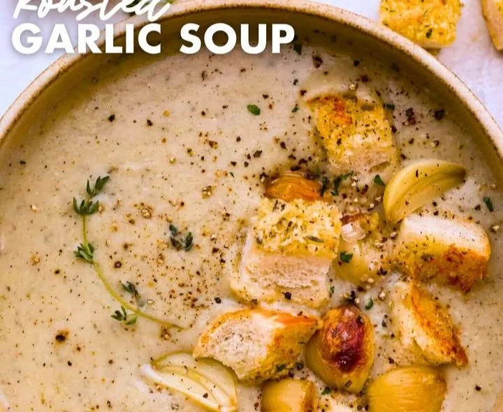 Delicious bowl of roasted garlic soup garnished with herbs