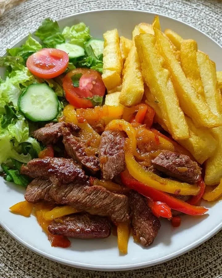 Steak fajitas with fries and a fresh garden salad on a plate.