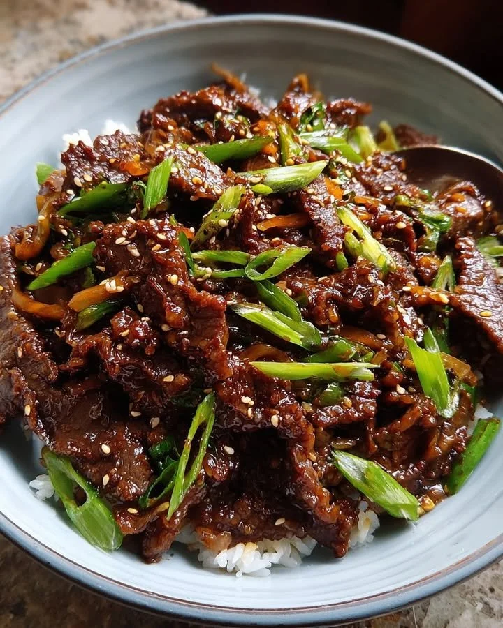 Plate of sticky caramelized Mongolian beef garnished with garlic and a soy glaze