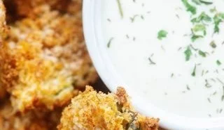 Crispy air fried pickles served on a plate with dipping sauce.