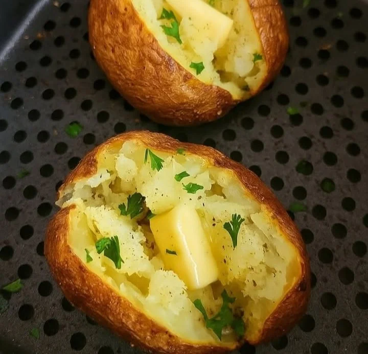 Air fryer baked potatoes served on a plate with toppings.