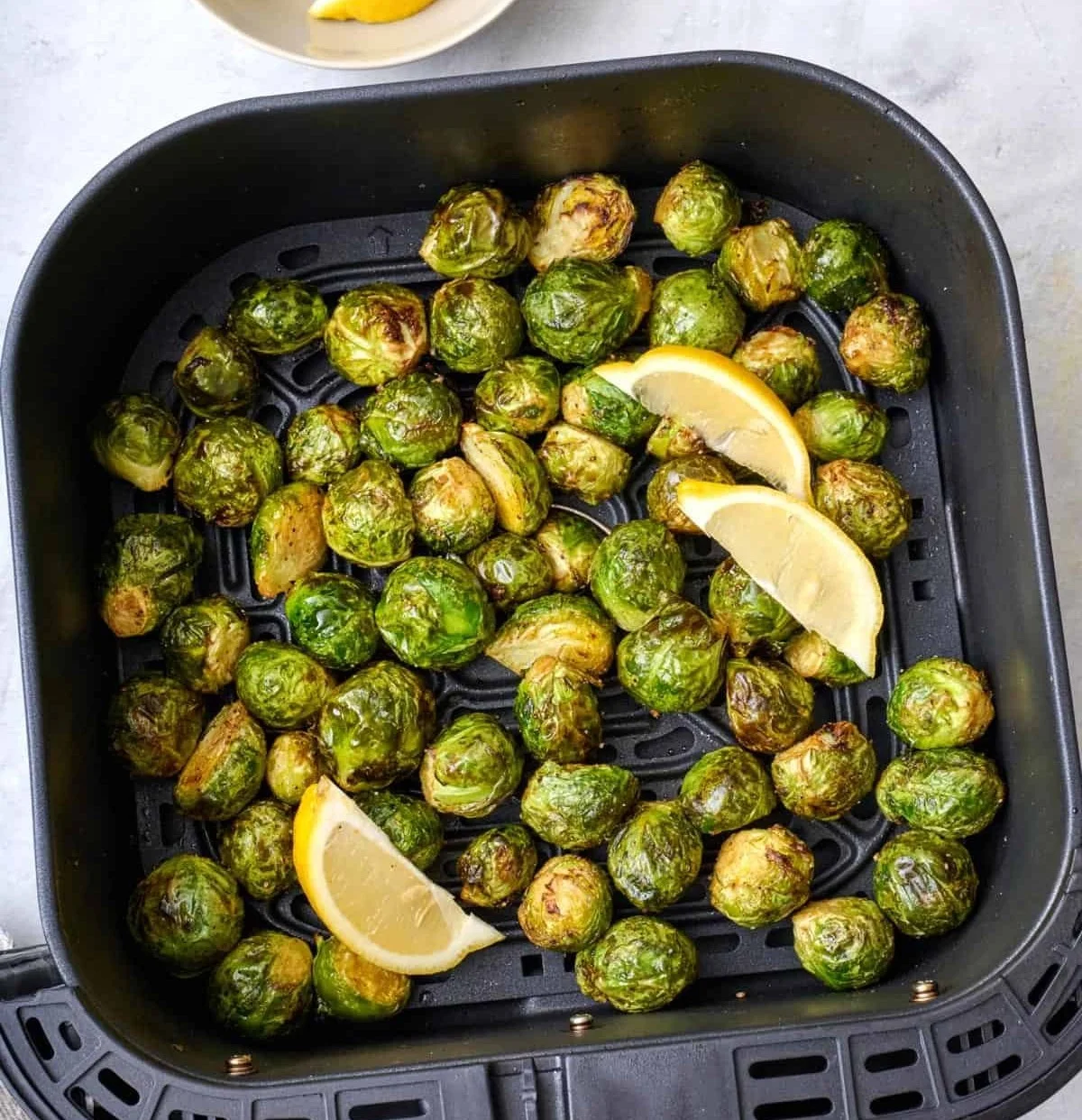 Crispy air fryer Brussels sprouts served in a bowl garnished with herbs.