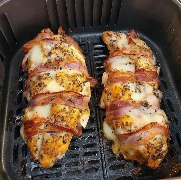 Delicious air fryer chicken breasts on a plate garnished with herbs
