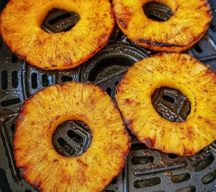 Delicious caramelized air fryer pineapple slices served on a plate.