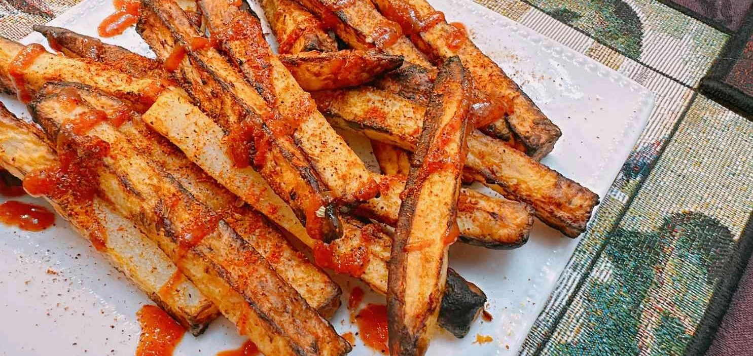 Crispy Air Fryer Sriracha Fries topped with hot sauce and herbs