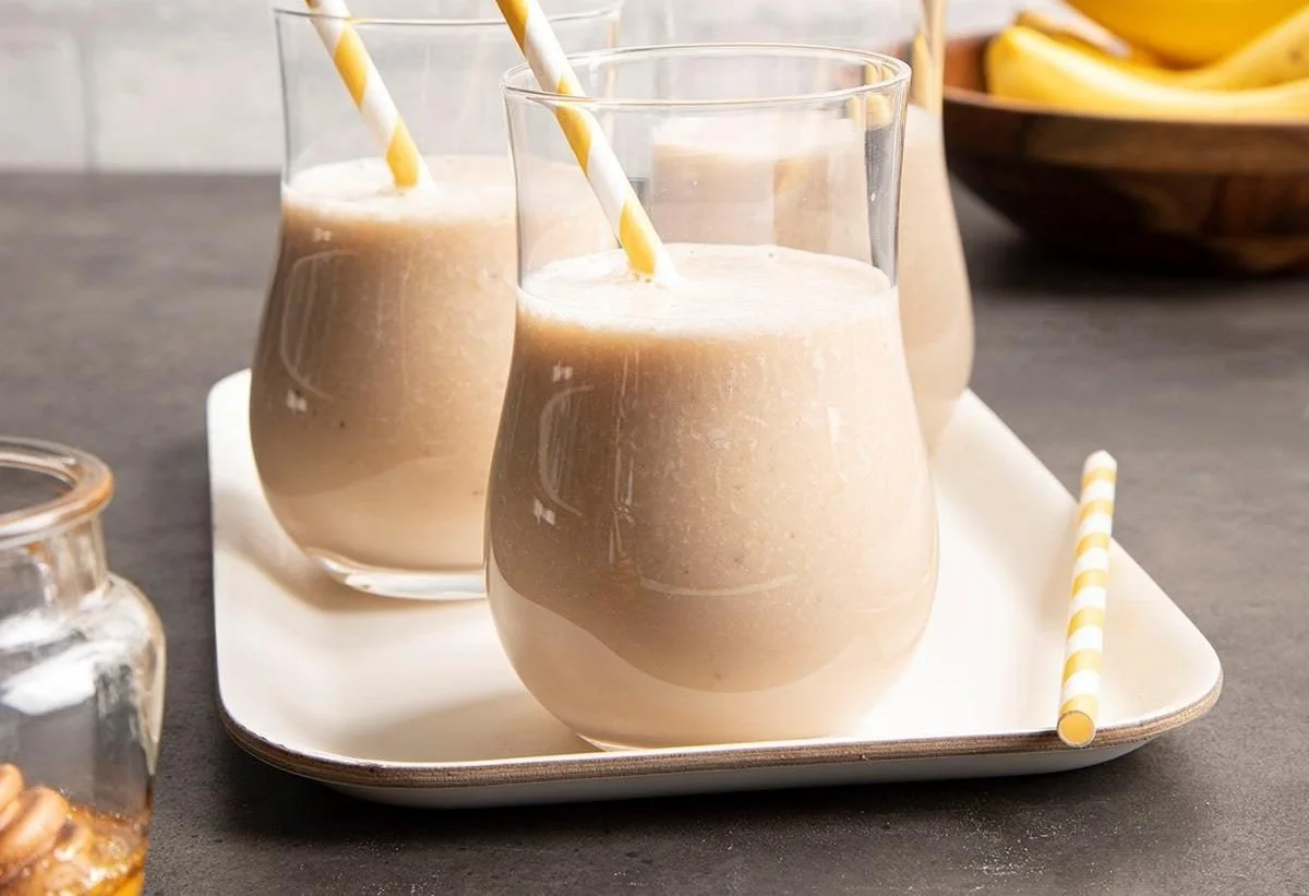 Delicious banana smoothie in a glass with fresh bananas