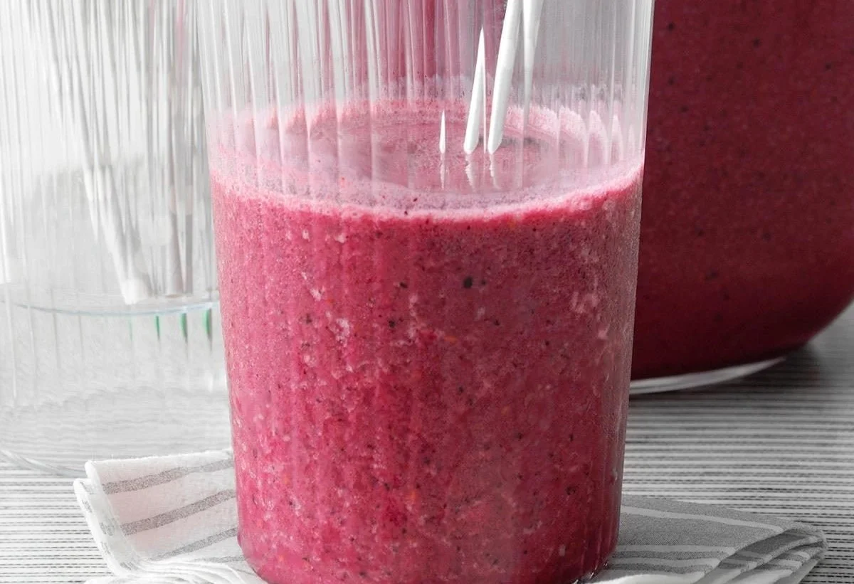 A colorful berry breakfast smoothie topped with fresh fruits and seeds.