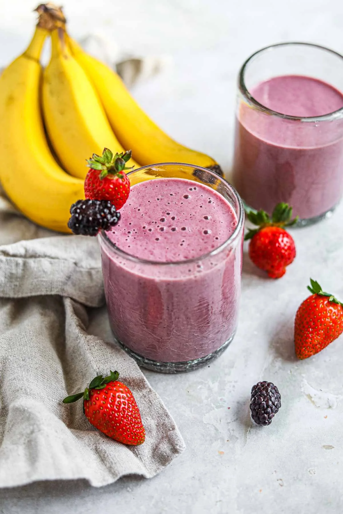 Blackberry strawberry banana smoothie in a glass topped with fresh fruits