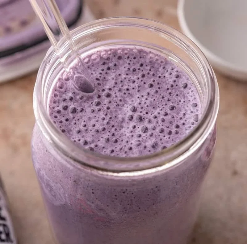 Homemade blueberry protein shake in a glass with fresh blueberries
