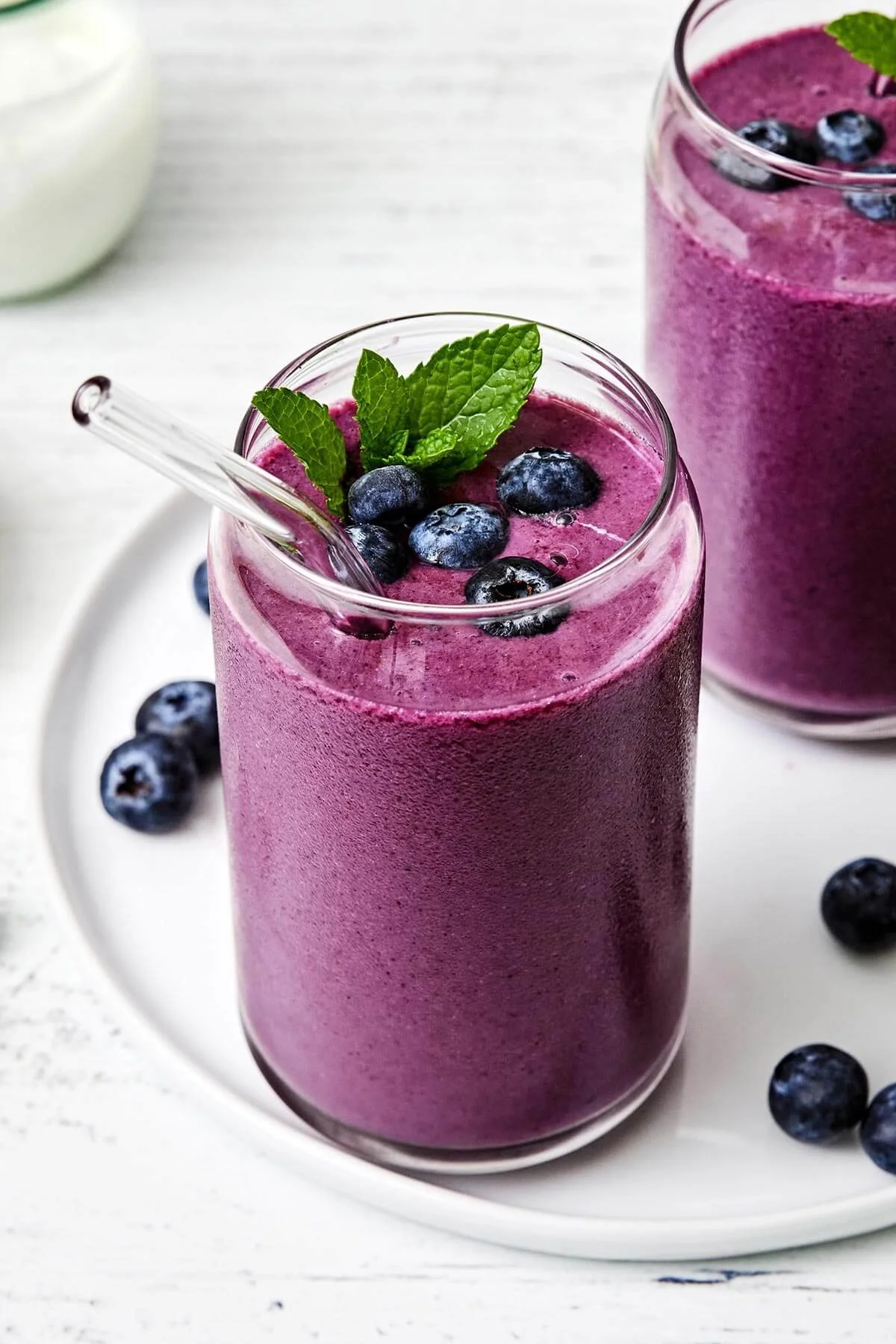 A refreshing blueberry smoothie topped with fresh blueberries and mint leaves.