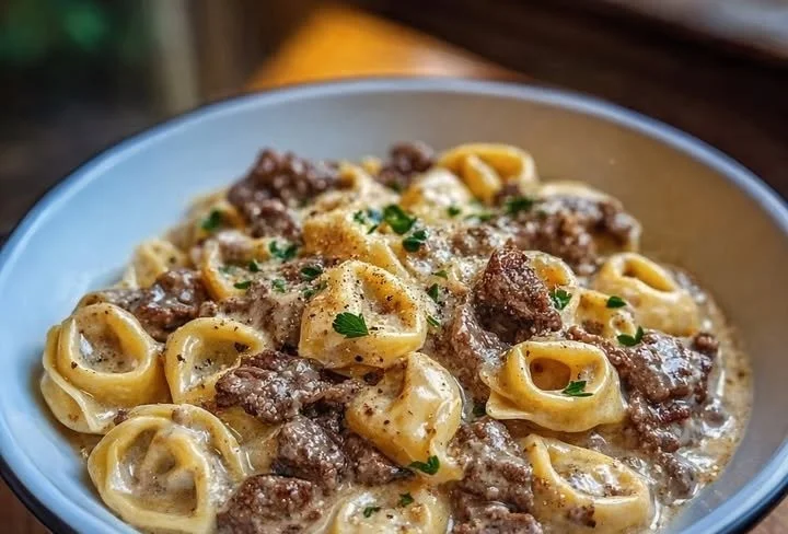 Plate of cheesesteak tortellini in rich provolone sauce garnished with herbs