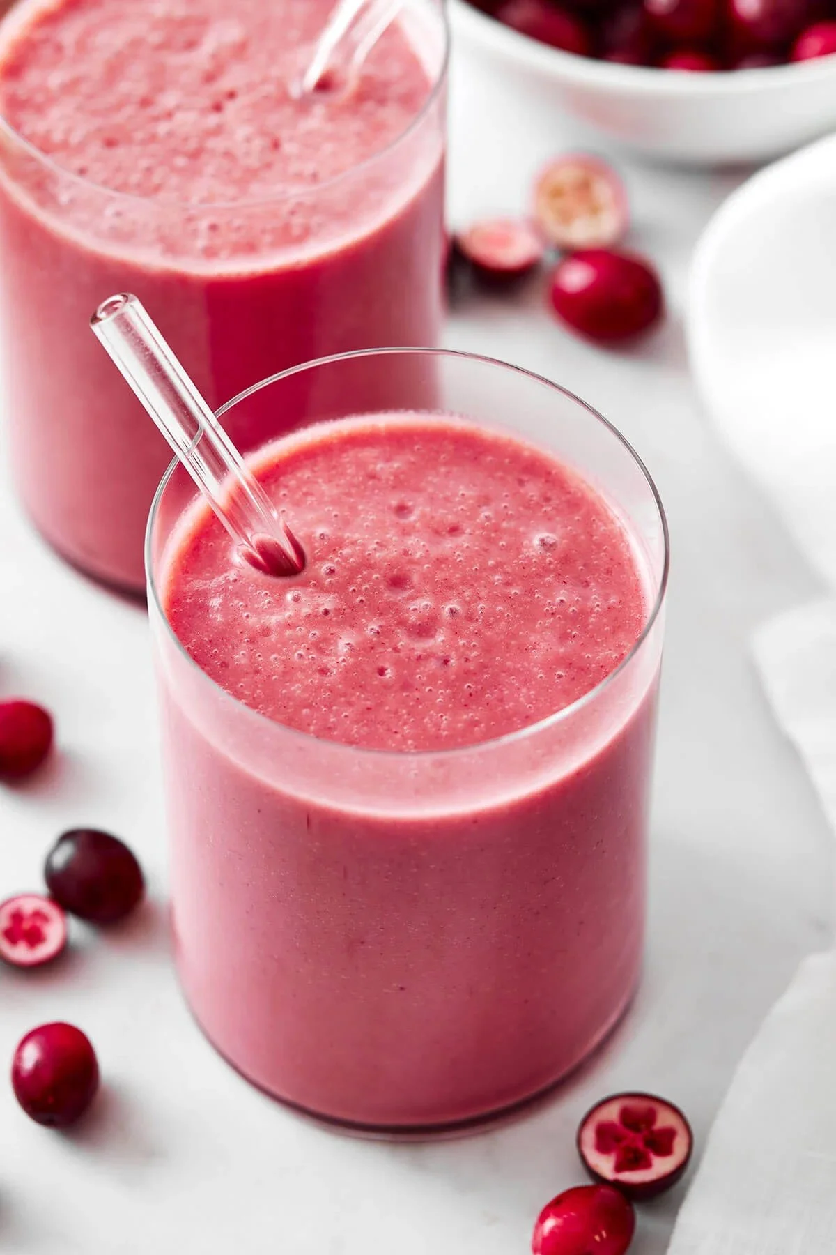 A vibrant cranberry smoothie with fresh fruit and yogurt in a glass.