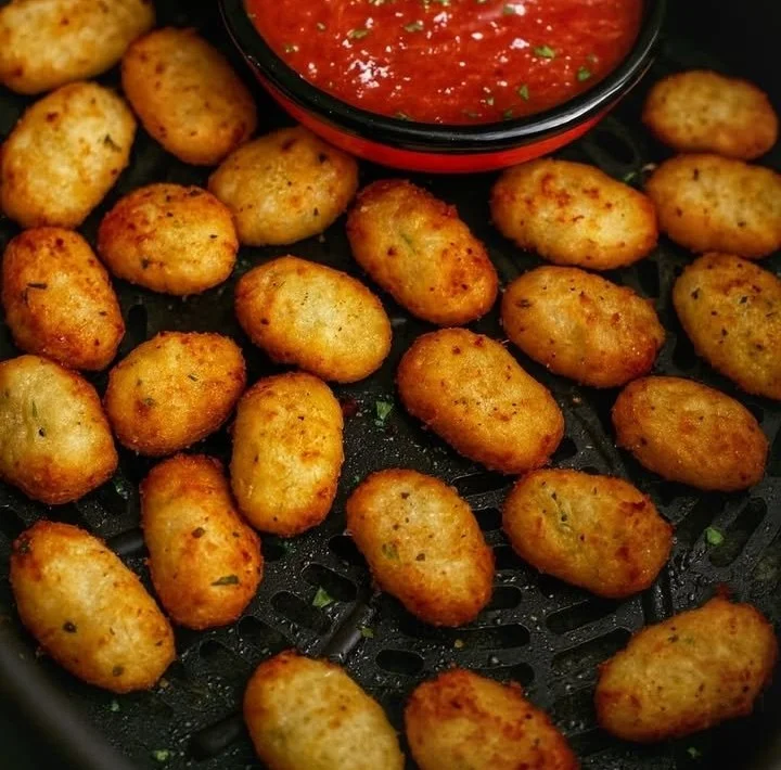 Crispy air fryer gnocchi served in a bowl with herbs and sauce.