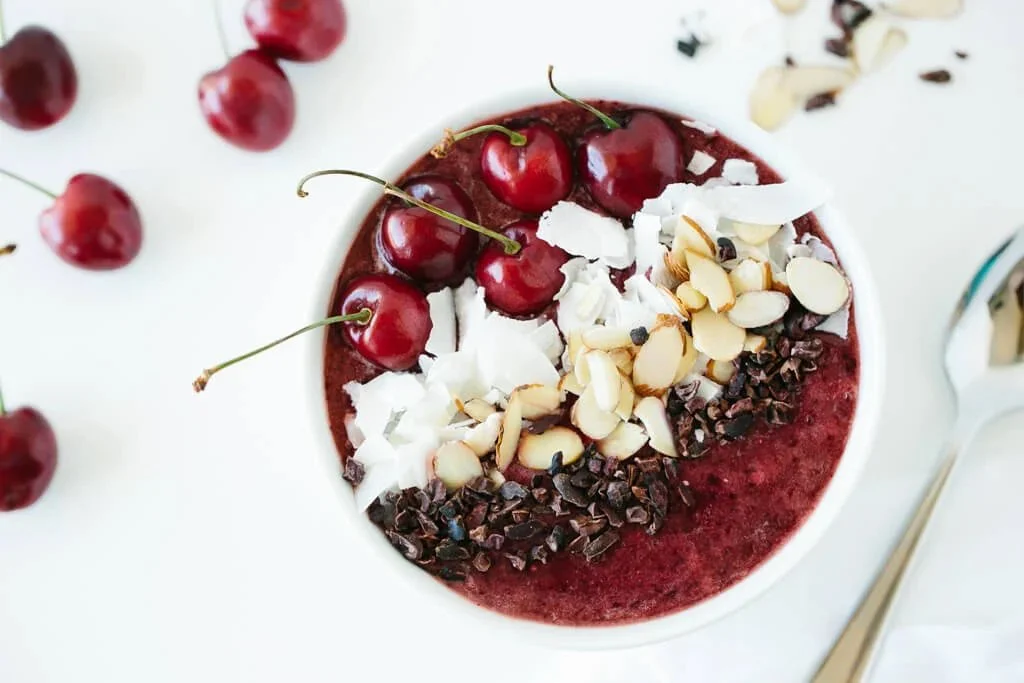 Delicious dark cherry smoothie bowl garnished with fresh fruits and nuts