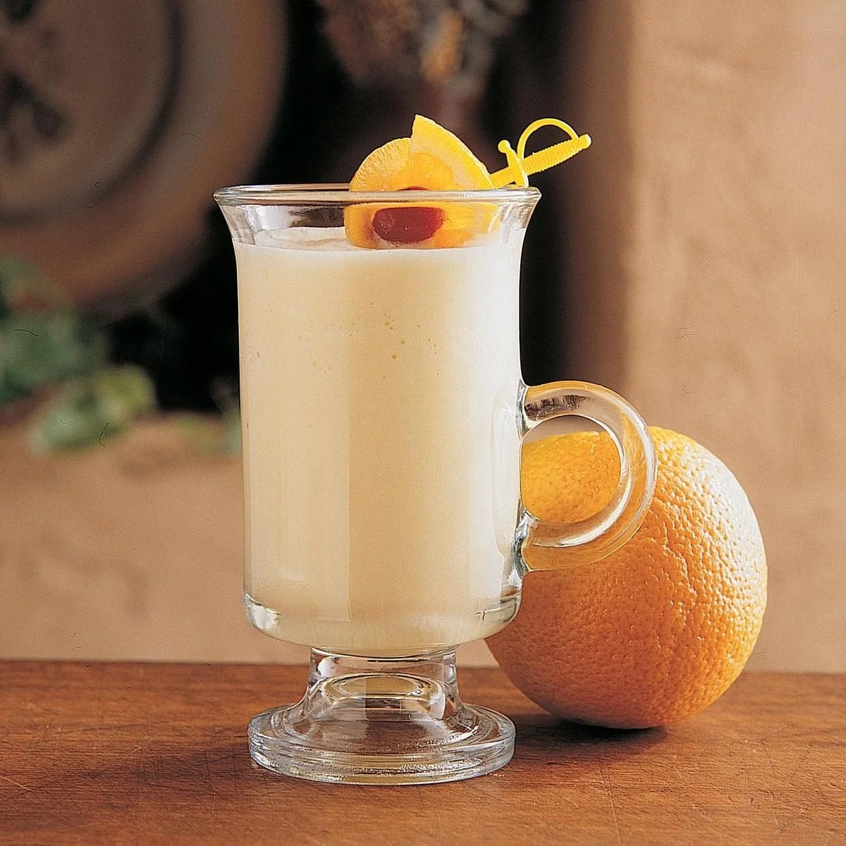 Frosty orange smoothie served in a glass with fresh fruit garnish