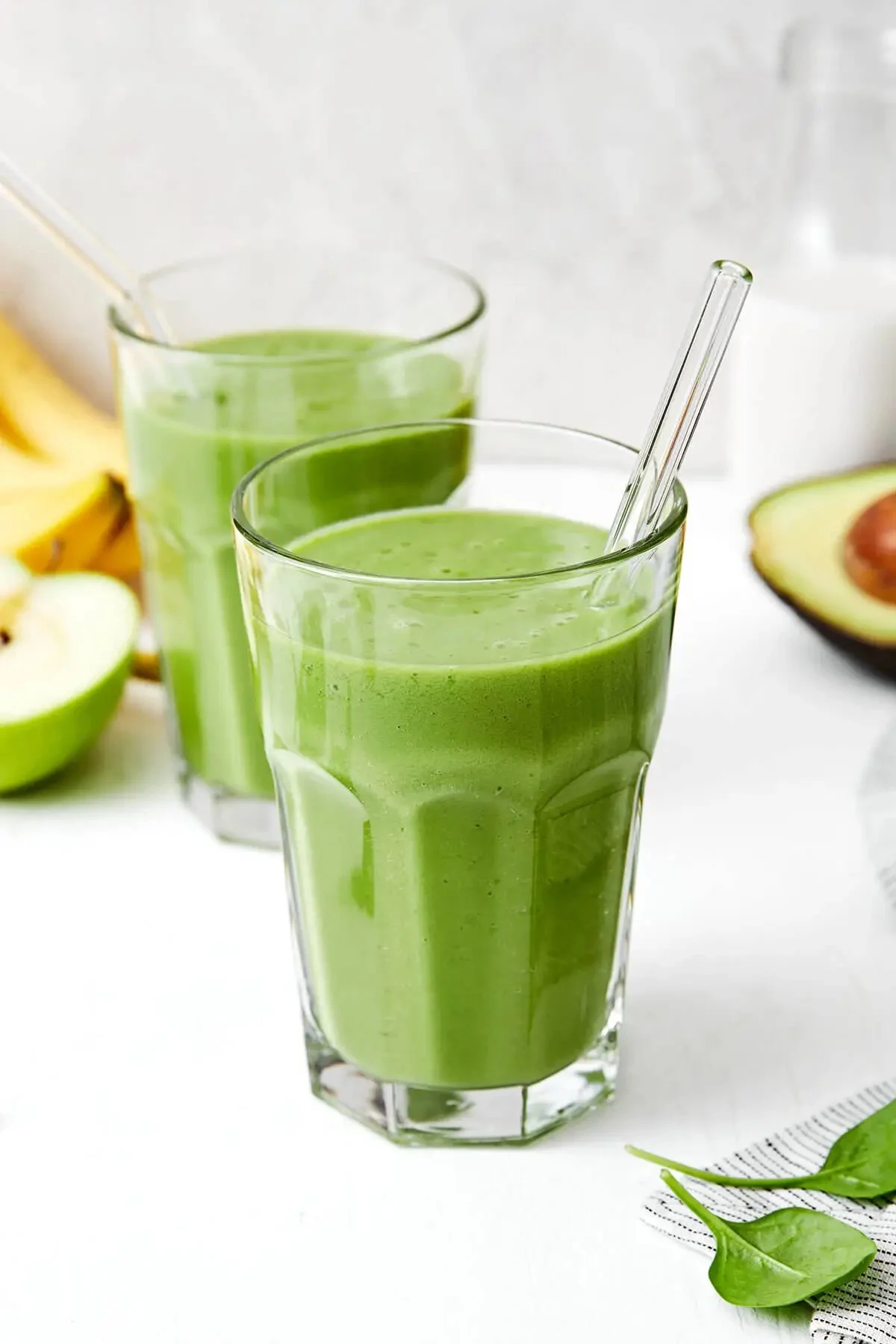 A vibrant green smoothie made with spinach, banana, and avocado in a glass.
