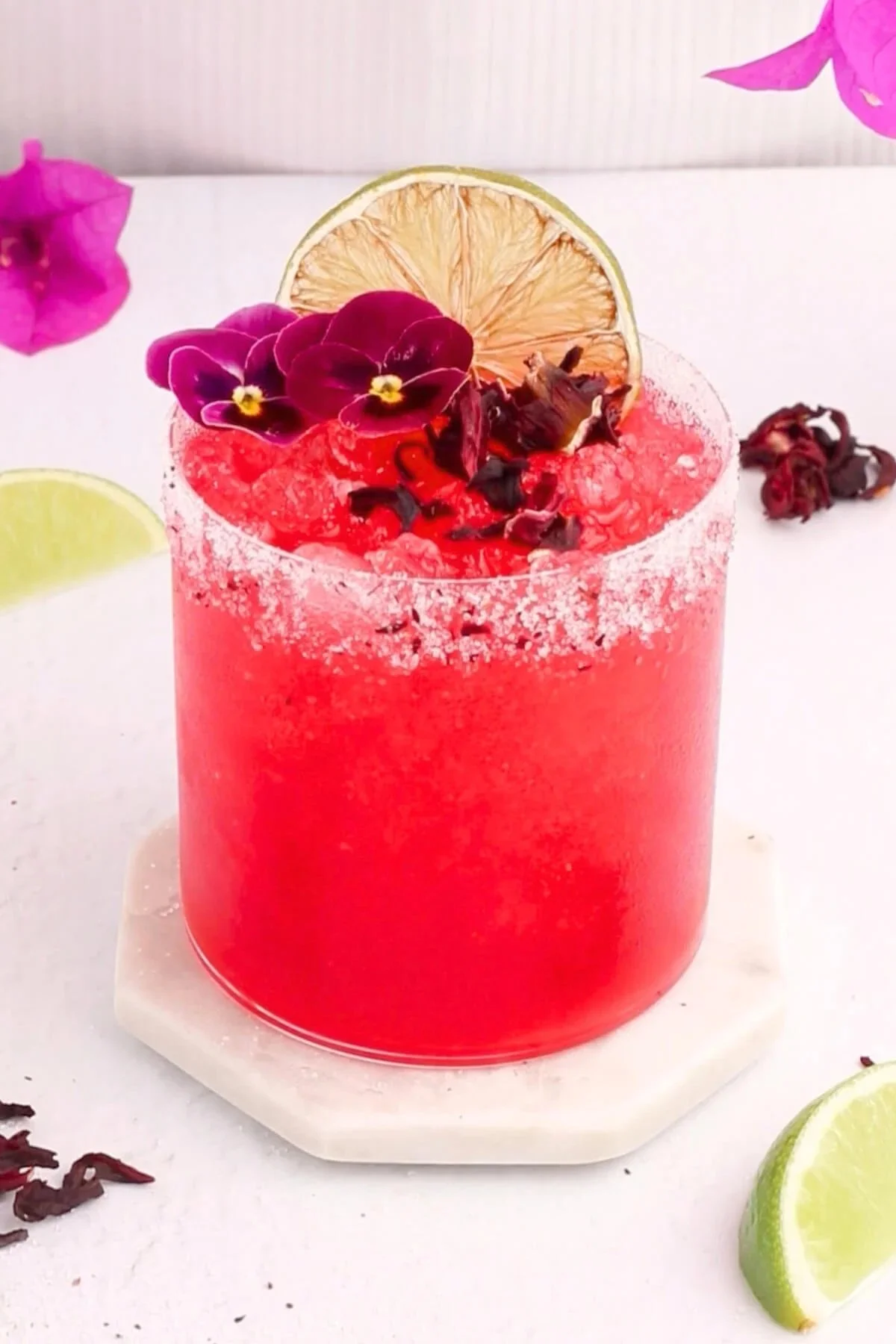 Low sugar Hibiscus Margarita mocktail in a glass with a garnish of hibiscus flower.