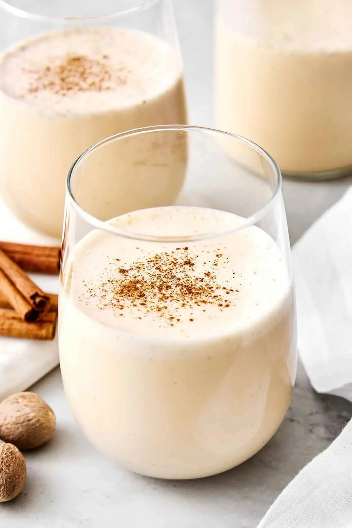 A glass of homemade eggnog garnished with nutmeg and cinnamon