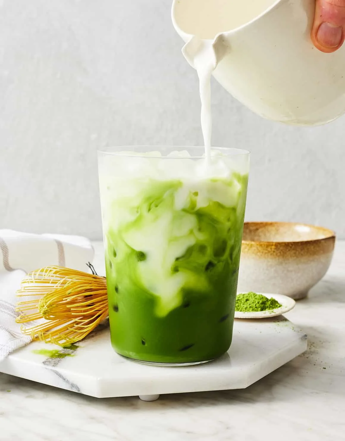 Iced matcha latte in a glass with ice cubes and a straw.