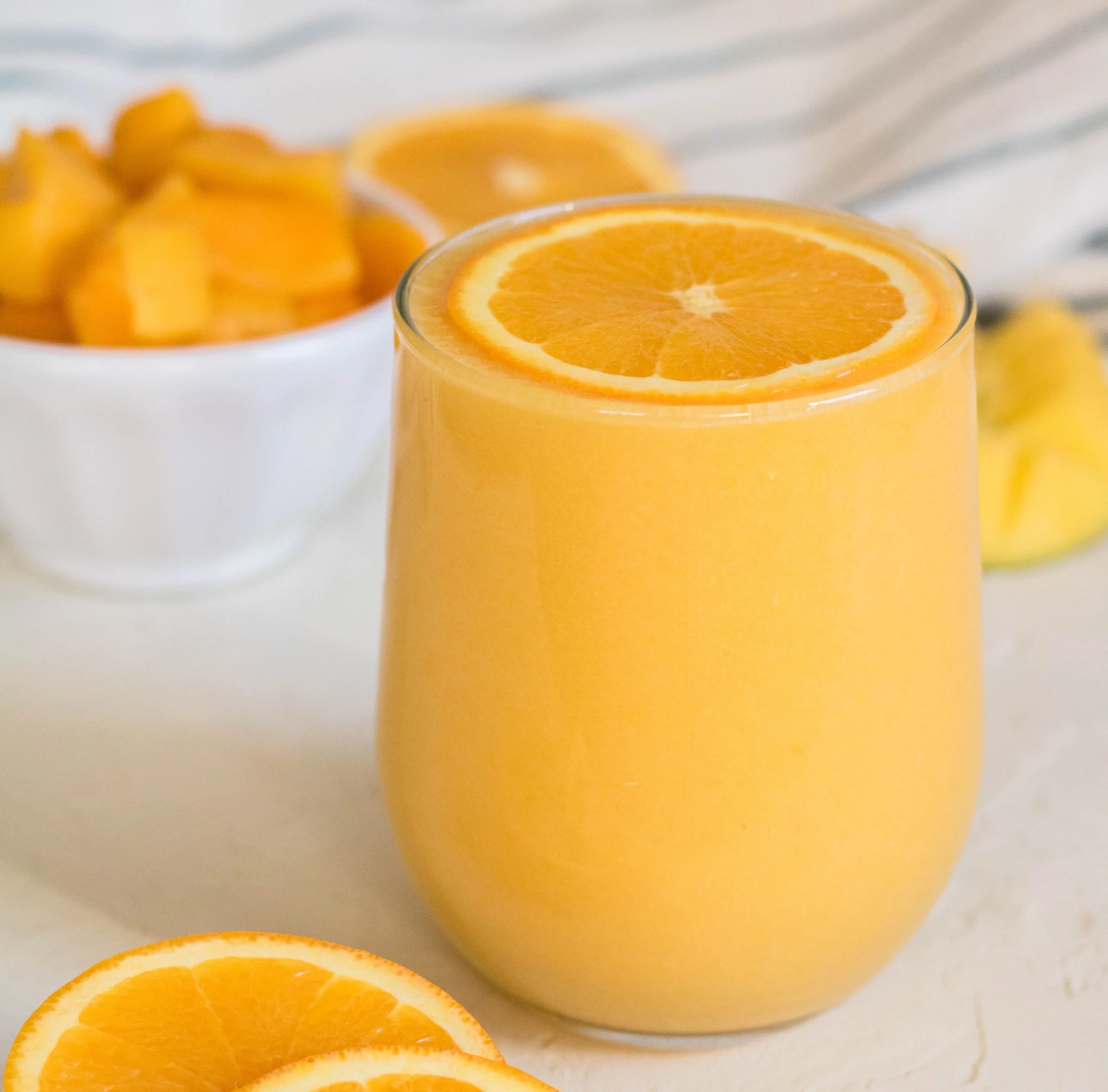 Immune boosting orange mango smoothie in a glass with fresh fruits