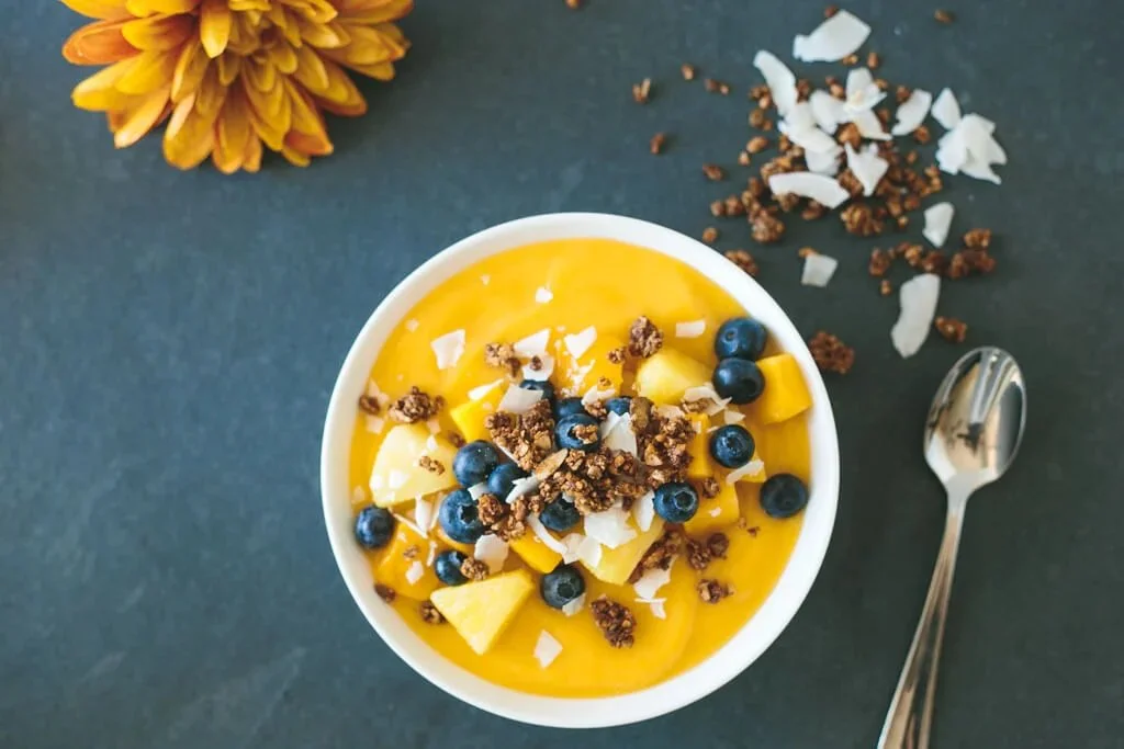 Delicious mango smoothie bowl topped with fresh fruits and seeds