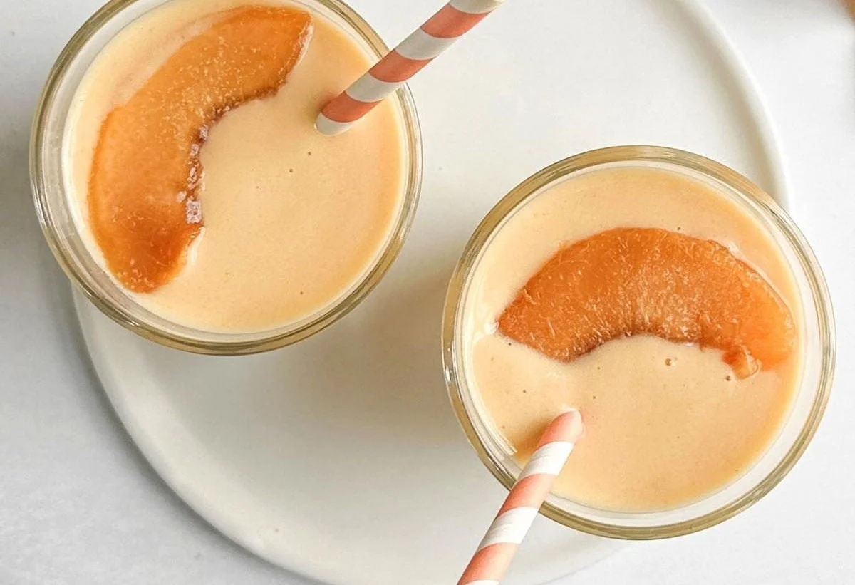 Delicious homemade peach smoothie in a glass with fresh peaches