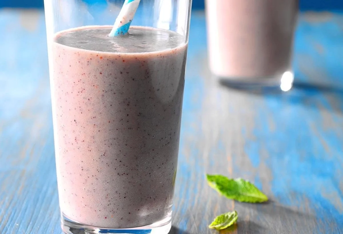 A colorful array of healthy smoothies in different glasses garnished with fruits.