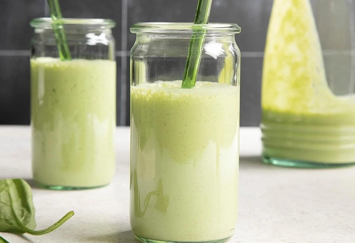 A refreshing spinach smoothie with fruits in a glass, promoting health benefits.