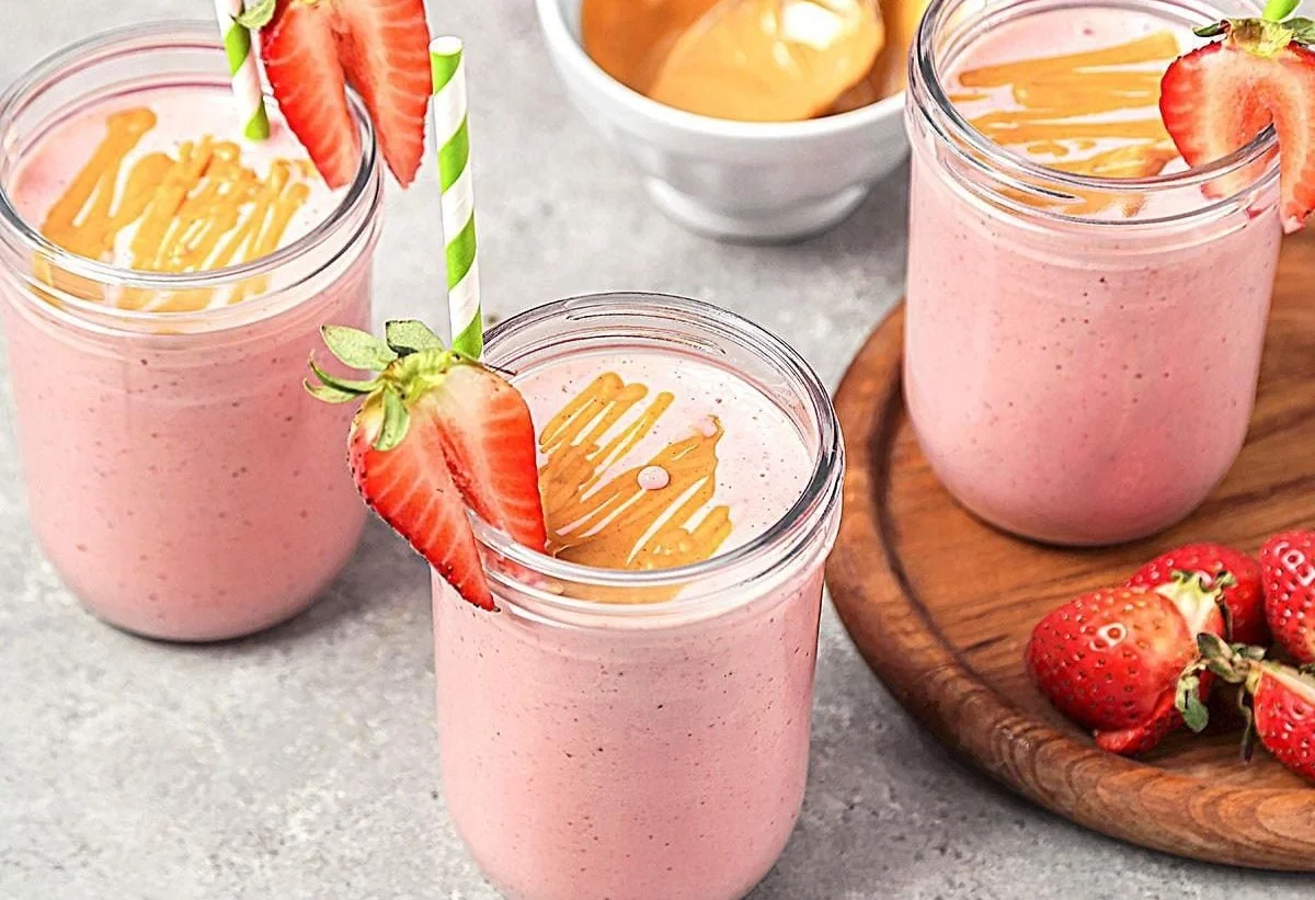 Strawberry banana smoothie with peanut butter in a glass, garnished with fresh strawberries.