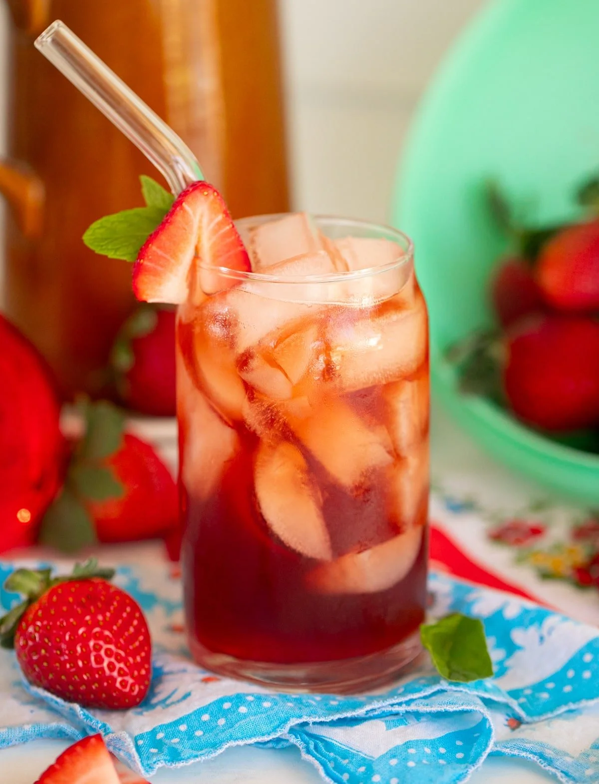 A glass of strawberry sweet tea garnished with fresh strawberries and mint leaves.