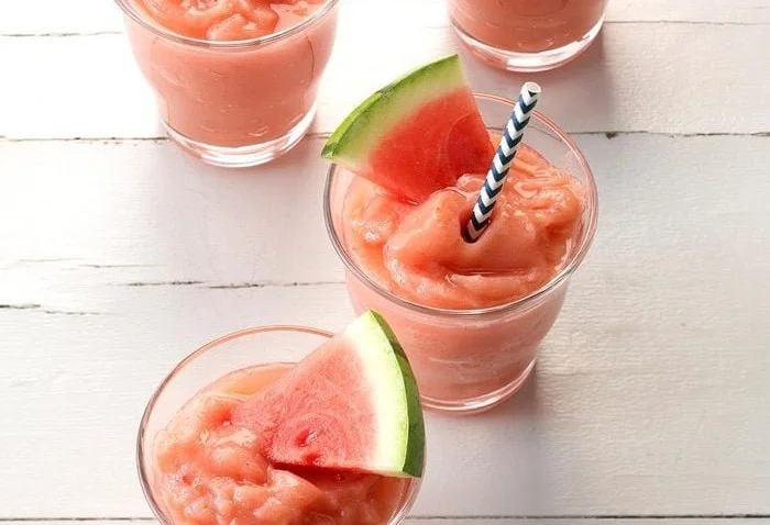 Delicious strawberry watermelon slush in a glass with ice and fresh fruit garnish.