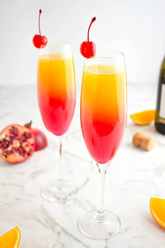Colorful Sunrise Mocktail served in a glass with an orange slice and cherry