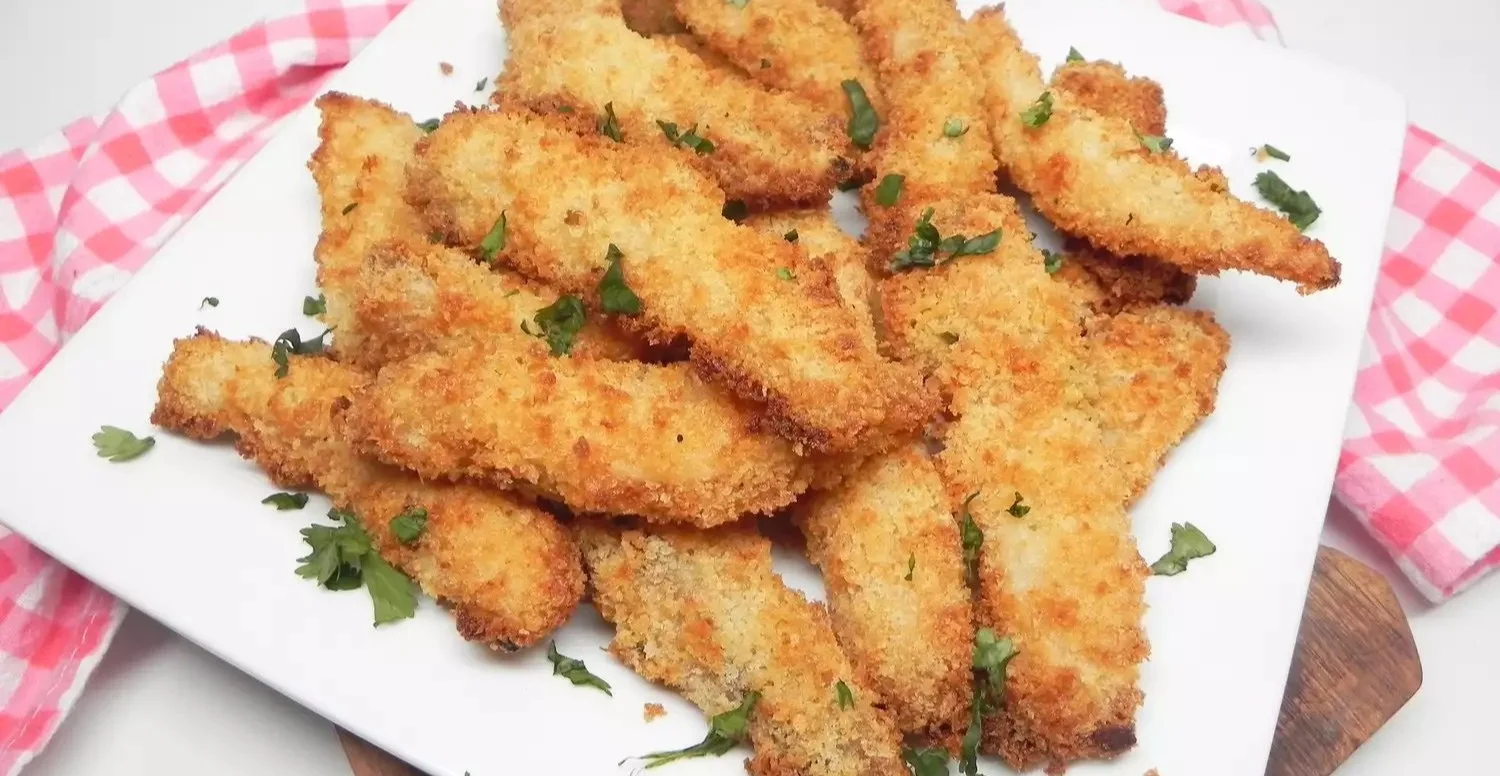Battered fish sticks with tartar sauce beside an air fryer.