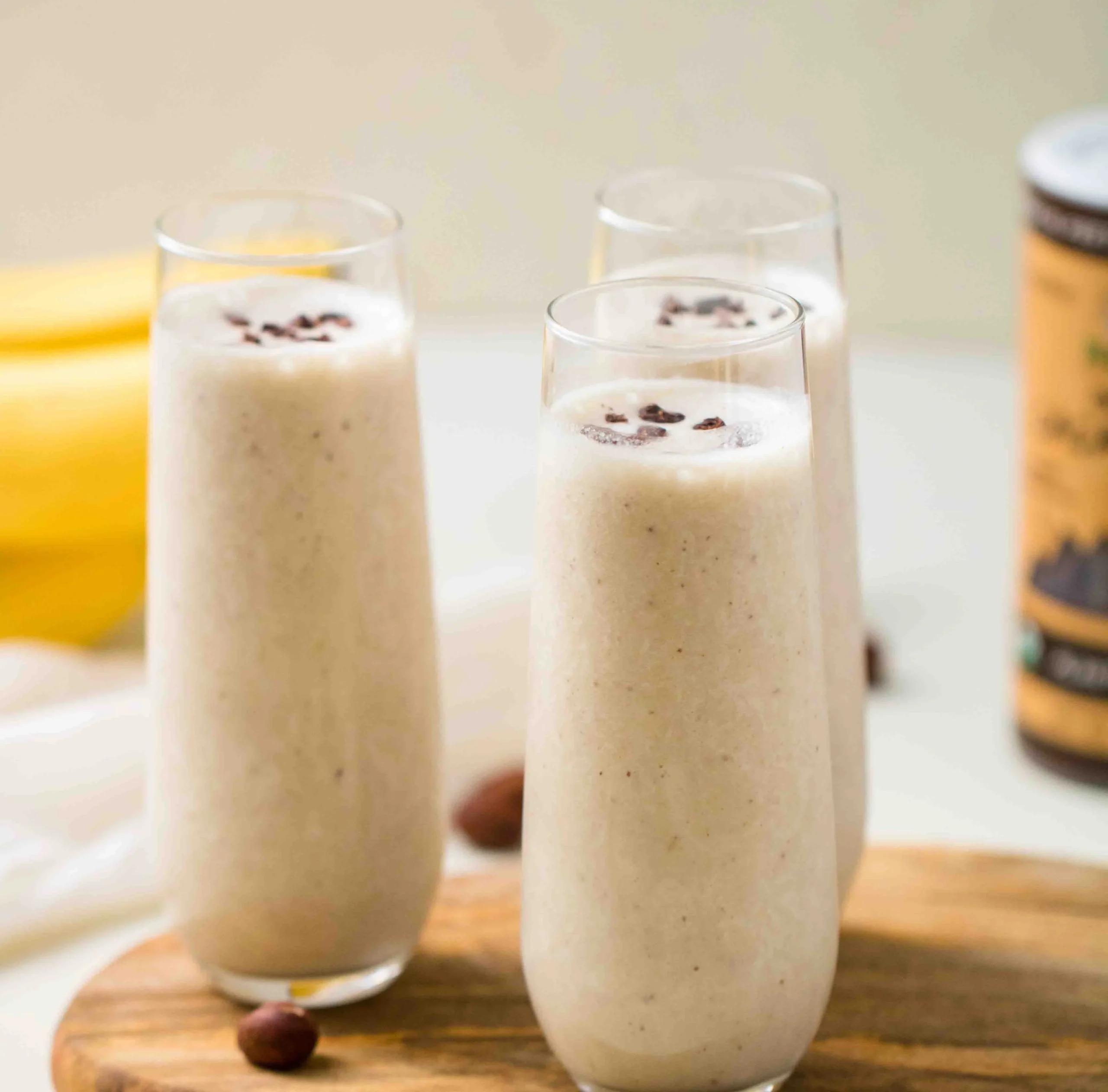 Toasted hazelnut smoothie with bananas in a glass garnished with hazelnuts.
