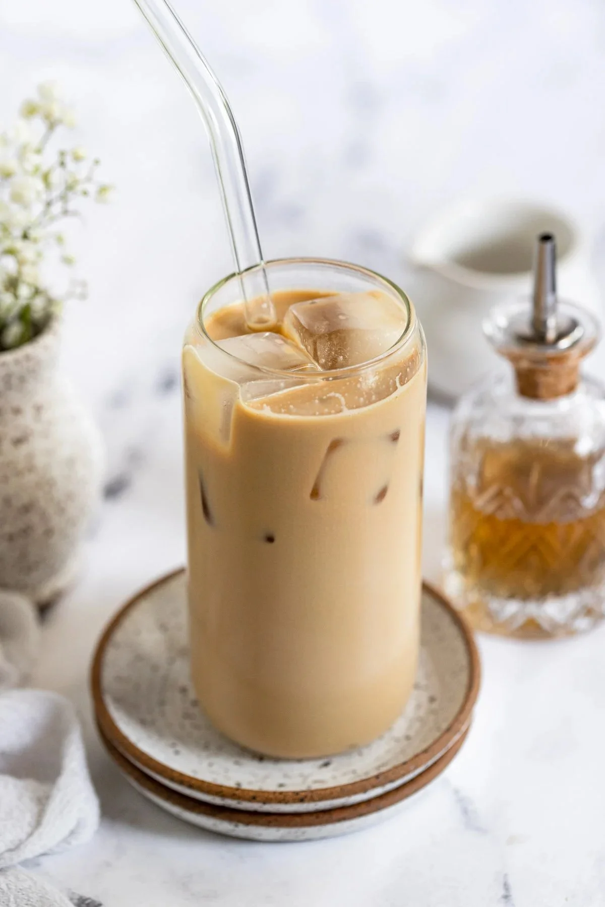 Delicious Vanilla Iced Latte served in a glass with ice and coffee beans.