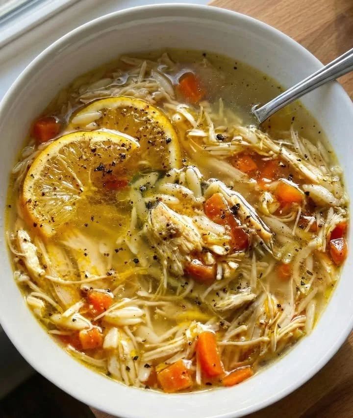 Bowl of delicious Crockpot Chicken Lemon Soup garnished with fresh herbs