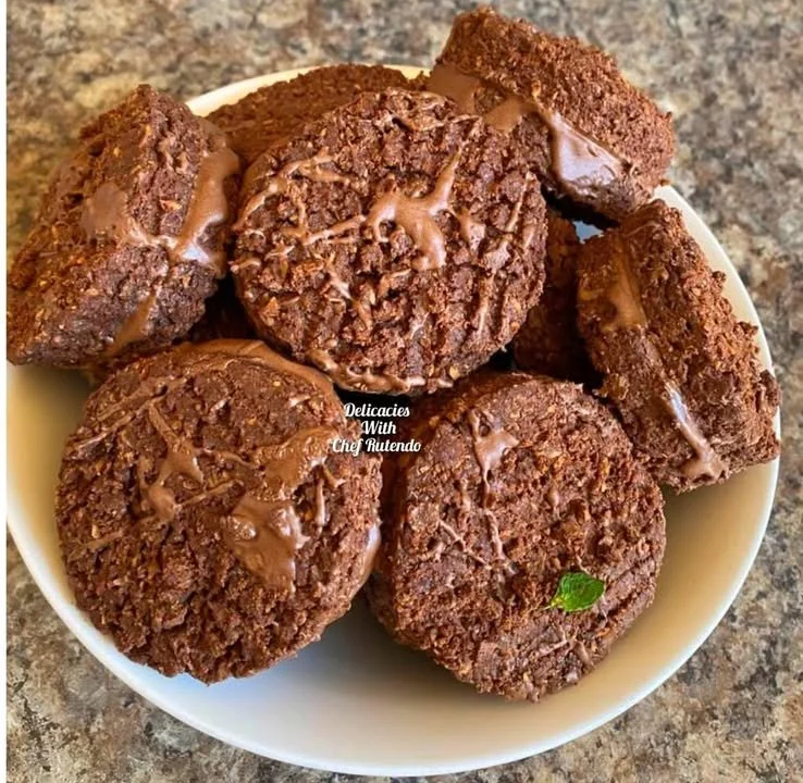 Homemade coconut chocolate biscuits stacked on a plate.